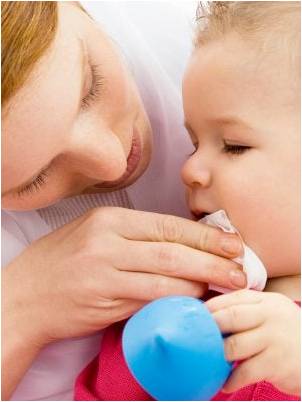 Mother cleaning her baby's mouth after vomiting.